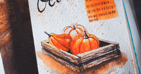 Calendar showing month of October with orange pumpkins in foreground